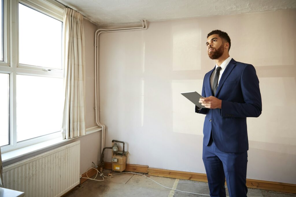 Male Realtor With Digital Tablet Carrying Out Valuation On Property For Renovation