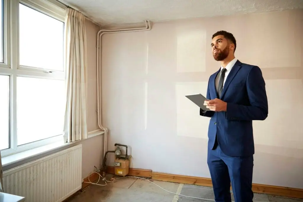 Male Realtor With Digital Tablet Carrying Out Valuation On Property For Renovation