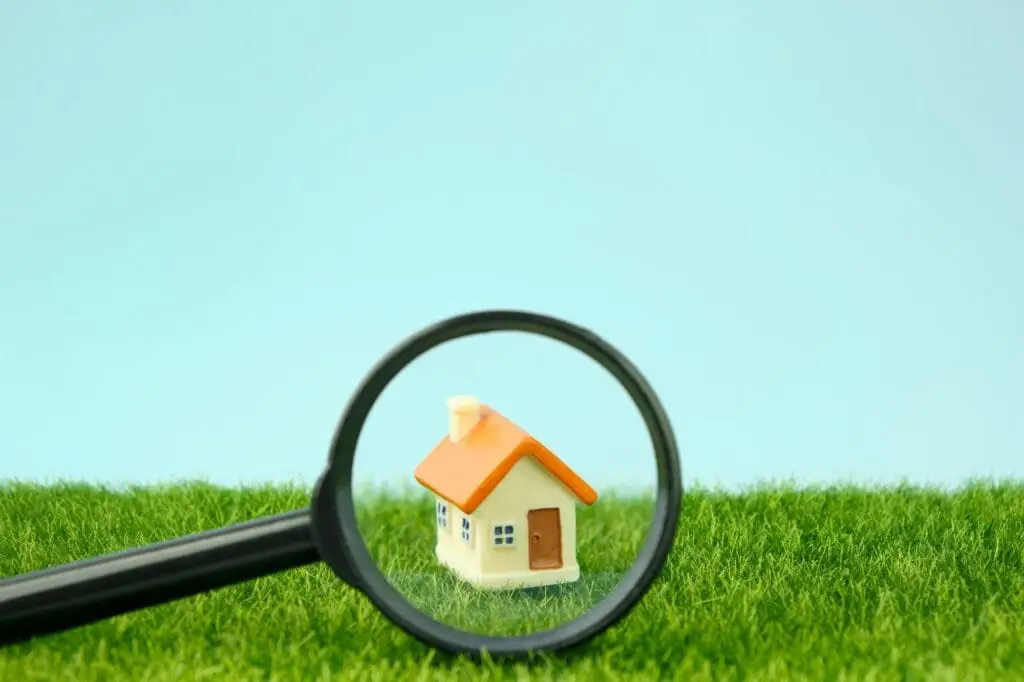Small houses under a magnifying glass. Real estate search concept, purchase and sale of housing
