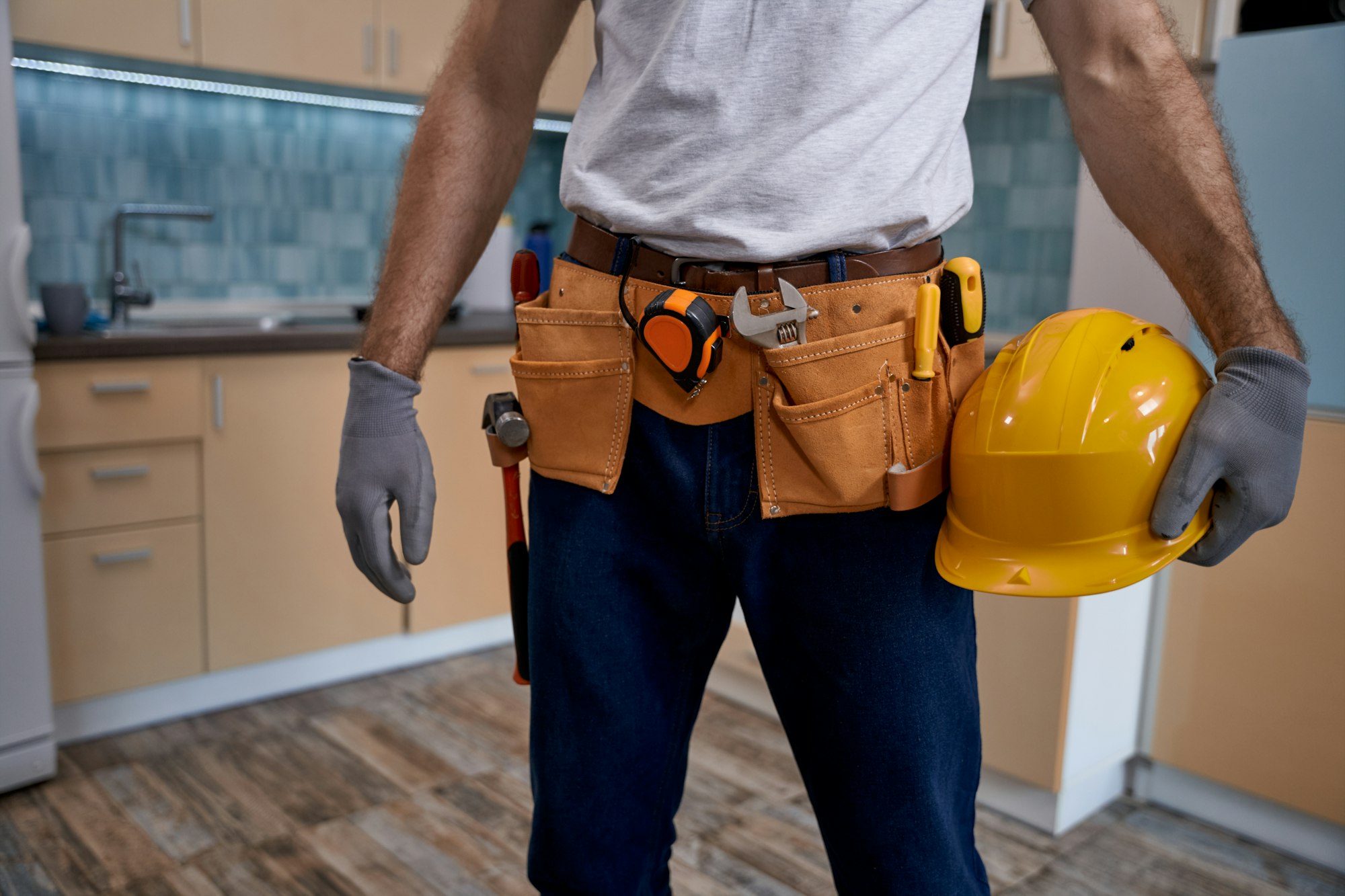 Young repairman with tools belt and hard helmet