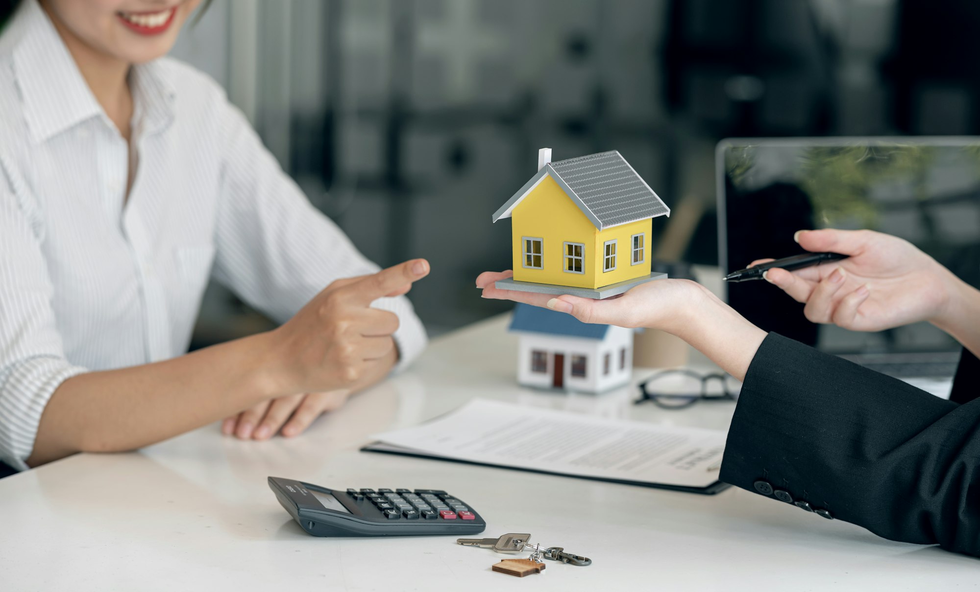 Female real estate agent and insurance salesman giving a sample house to a client.