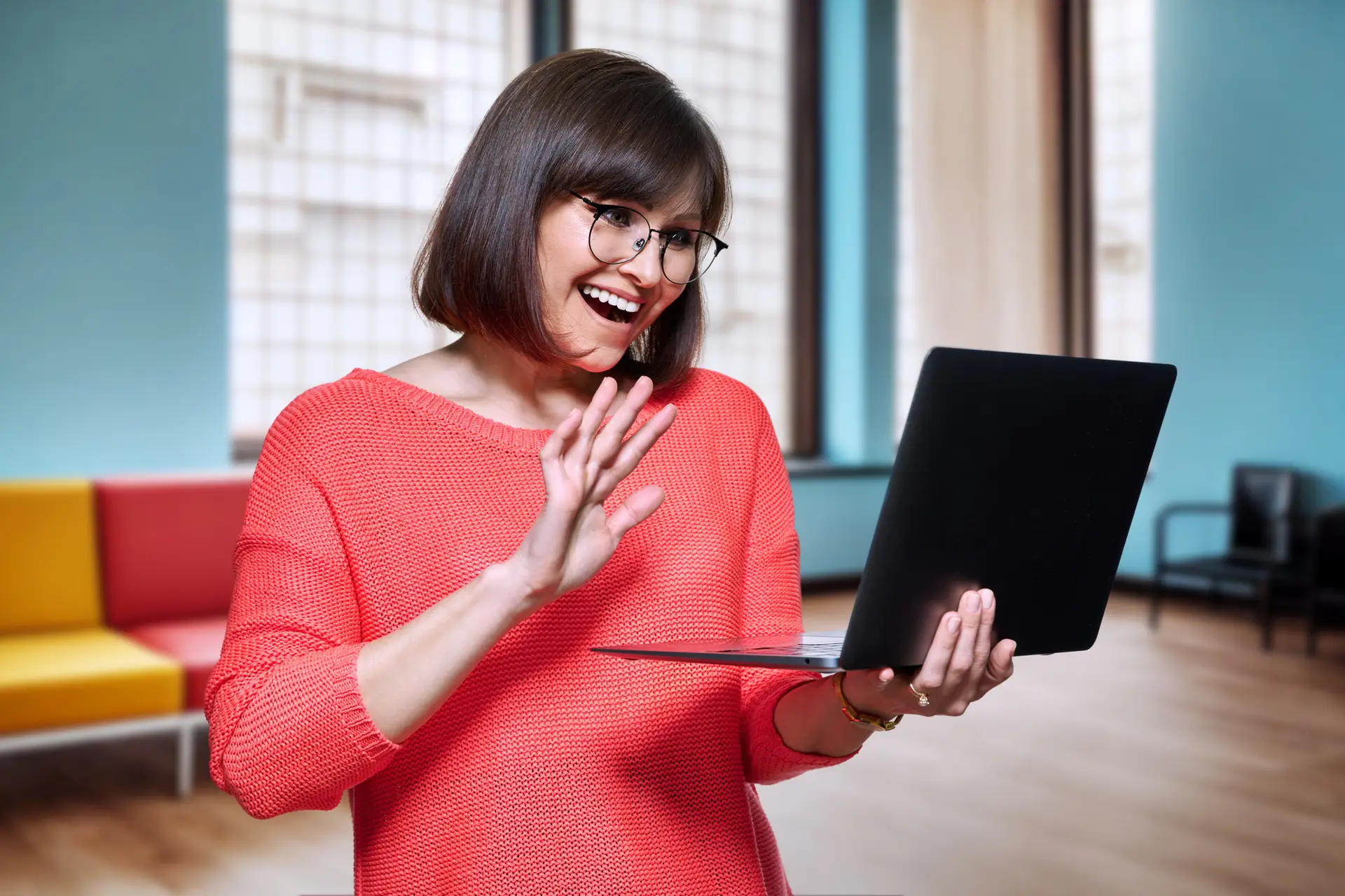 Middle aged female in office with laptop, using video call
