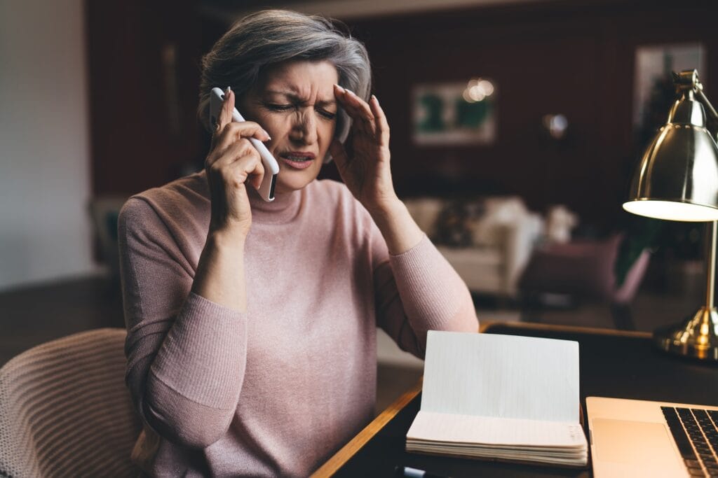 Tired senior woman speaking on smartphone