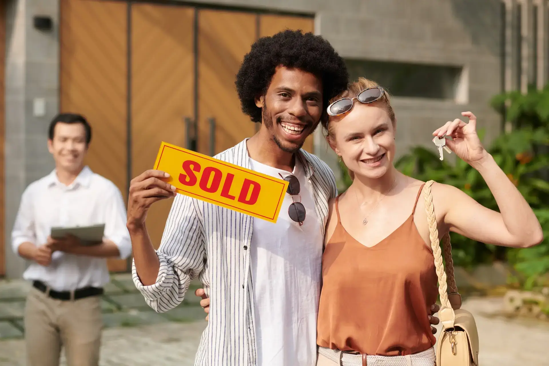 Diverse Couple Showing Sold Sign